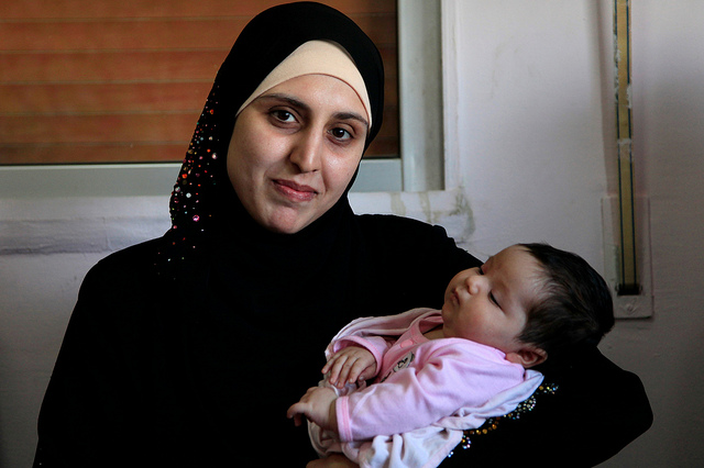 A Syrian refugee woman with her 25-day old daughter in an International Rescue Committee clinic in Northern Jordan. (Photo: Russell Watkins)