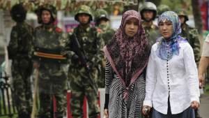 Two ethnic Uighur women pass Chinese paramilitary policemen standing guard outside the Grand Bazaar in the Uighur district of the city of Urumqi in China's Xinjiang region on July 14, 2009. A mosque was closed and many businesses were shuttered a day after police shot dead two Muslim Uighurs, as ethnic tensions simmered in restive Urumqi.   AFP PHOTO / Peter PARKS (Photo credit should read PETER PARKS/AFP/Getty Images)